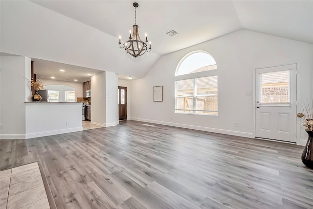 unfurnished living room featuring light wood-type flooring, baseboards, an inviting chandelier, and visible vents