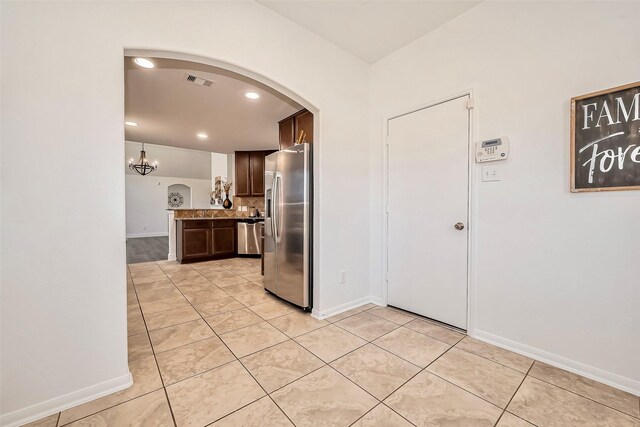 kitchen featuring arched walkways, visible vents, dark brown cabinets, and stainless steel appliances