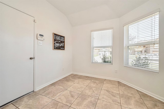 unfurnished room featuring vaulted ceiling, light tile patterned floors, and baseboards