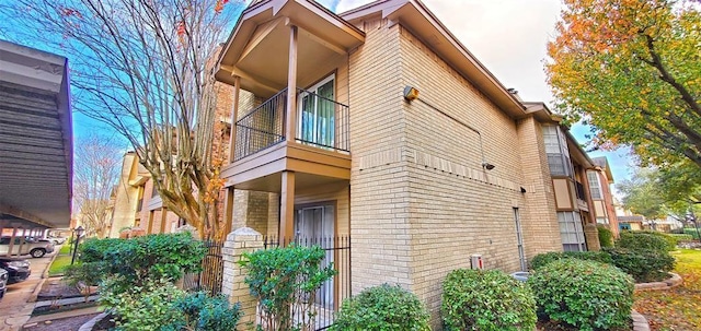 view of property exterior with a balcony and brick siding