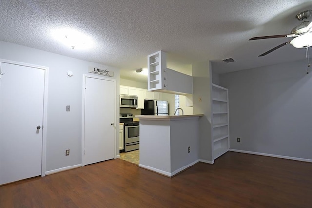 kitchen featuring ceiling fan, a peninsula, appliances with stainless steel finishes, wood finished floors, and a textured ceiling