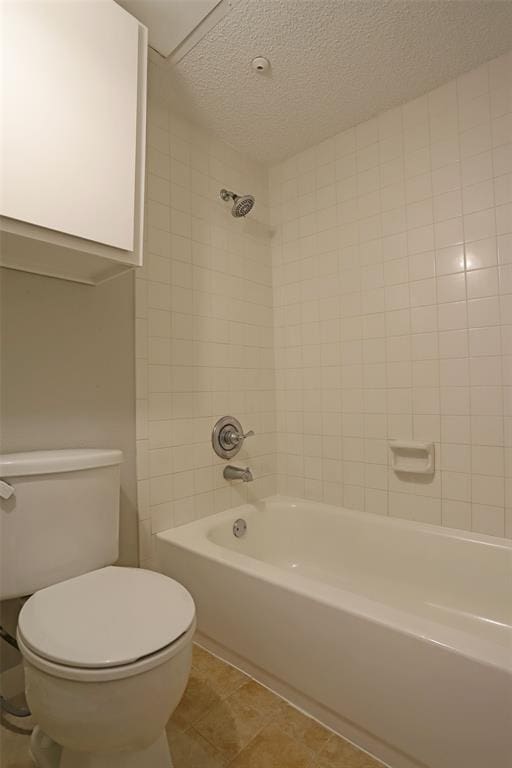 bathroom featuring tile patterned flooring, shower / washtub combination, toilet, and a textured ceiling