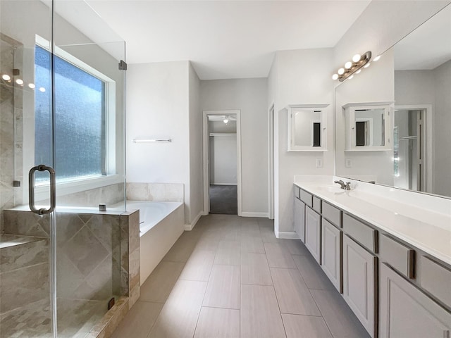 full bathroom with baseboards, a shower stall, vanity, and a garden tub