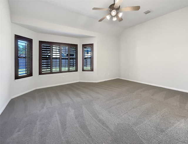 spare room featuring visible vents, lofted ceiling, dark colored carpet, baseboards, and ceiling fan