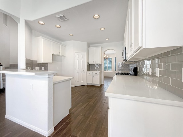 kitchen with visible vents, dark wood finished floors, a peninsula, white cabinetry, and range