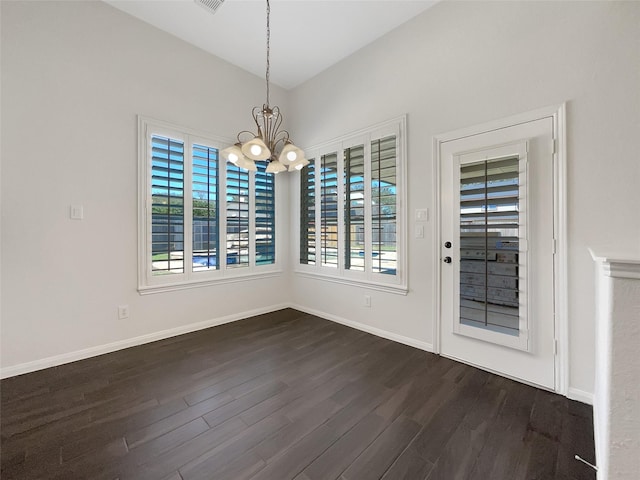 unfurnished dining area featuring dark wood finished floors, visible vents, baseboards, and an inviting chandelier