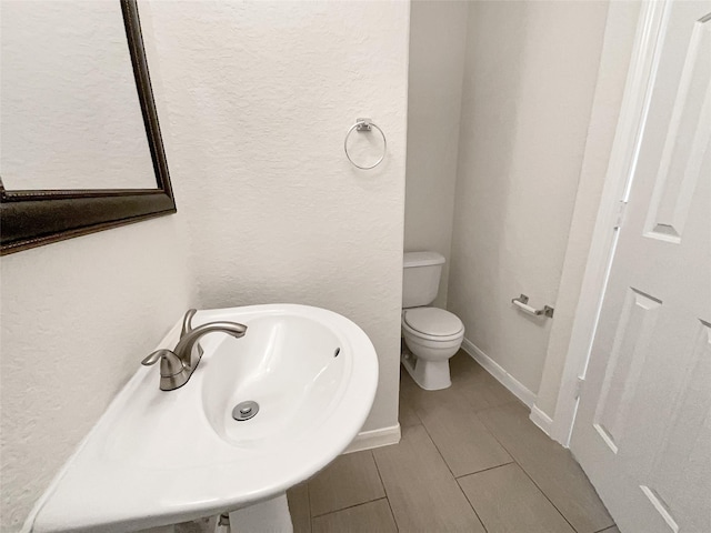 bathroom featuring a sink, baseboards, and toilet