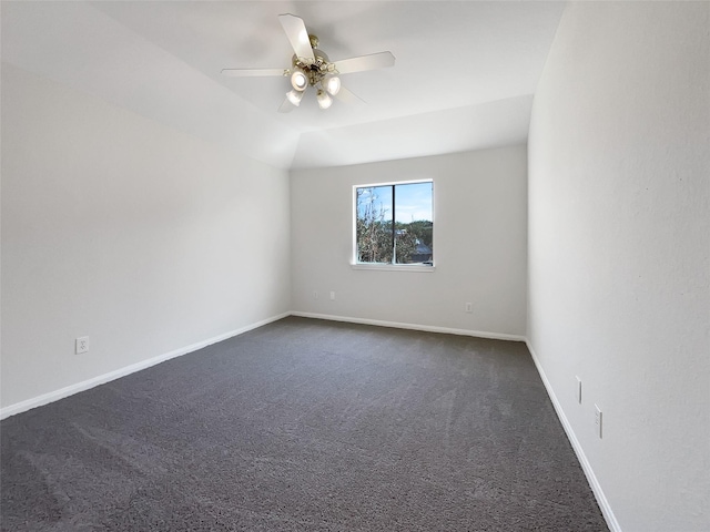 empty room featuring dark carpet, baseboards, lofted ceiling, and a ceiling fan