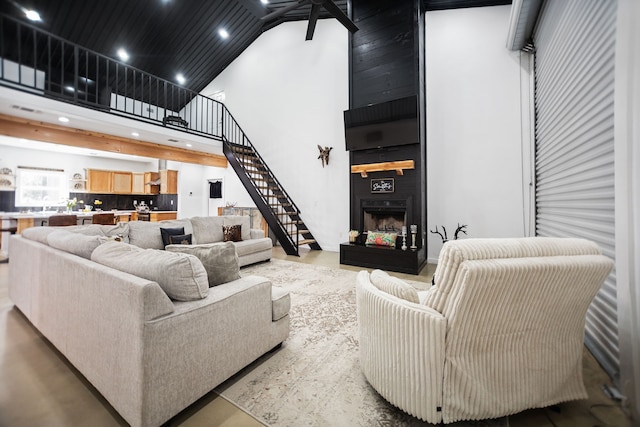 living area featuring stairway, recessed lighting, a fireplace, and a high ceiling