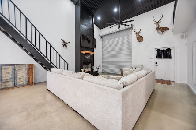 living area featuring stairway, a towering ceiling, concrete flooring, and a large fireplace