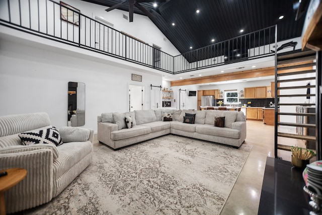 living area featuring a high ceiling, recessed lighting, a ceiling fan, and concrete flooring