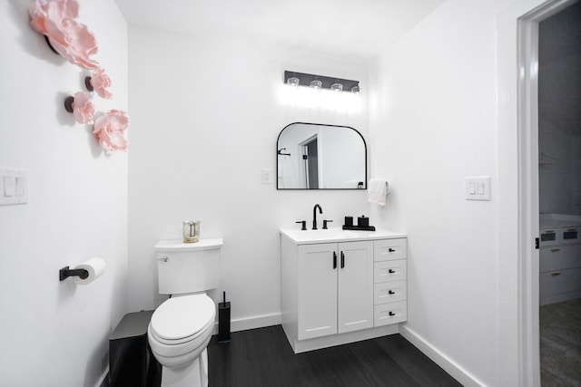 bathroom featuring vanity, toilet, wood finished floors, and baseboards