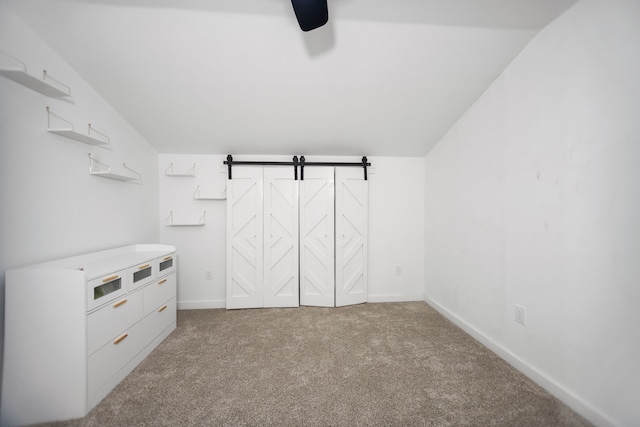 interior space featuring a barn door, lofted ceiling, carpet, and ceiling fan