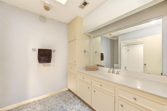 bathroom featuring vanity, visible vents, baseboards, walk in shower, and a textured ceiling