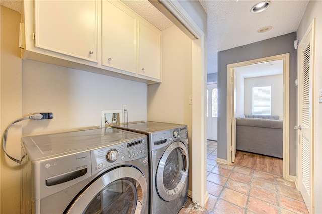 washroom featuring baseboards, cabinet space, independent washer and dryer, and a textured ceiling