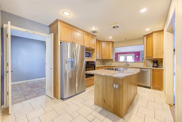 kitchen with black appliances, a sink, backsplash, a center island, and light stone countertops