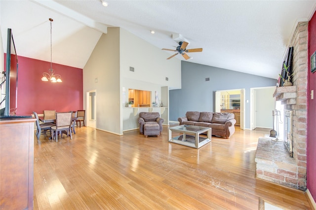 living room with a brick fireplace, vaulted ceiling with beams, baseboards, light wood-type flooring, and ceiling fan with notable chandelier