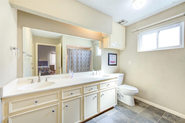 ensuite bathroom featuring a sink, visible vents, baseboards, and double vanity