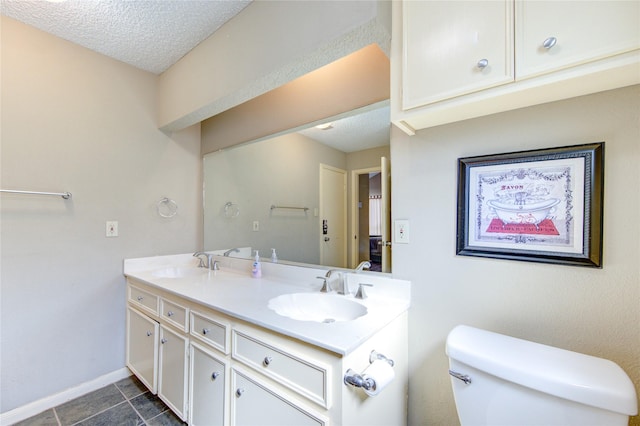 full bath featuring double vanity, toilet, a textured ceiling, and a sink