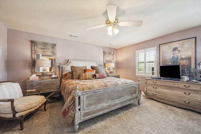 bedroom with visible vents, a textured ceiling, carpet flooring, and a ceiling fan