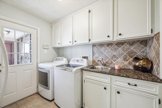 clothes washing area featuring light tile patterned floors, cabinet space, a sink, a textured ceiling, and washer and dryer