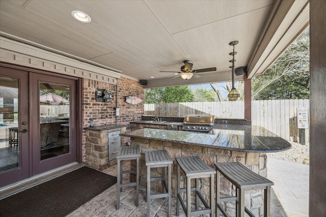 view of patio / terrace with fence, exterior kitchen, area for grilling, a sink, and french doors