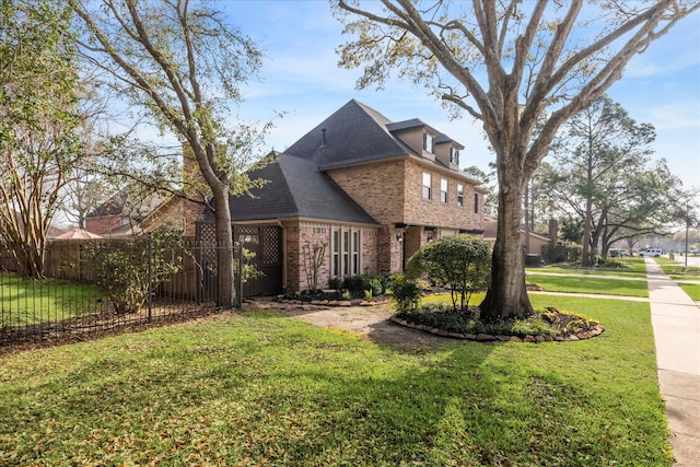 view of front of property with brick siding, roof with shingles, a front lawn, and fence