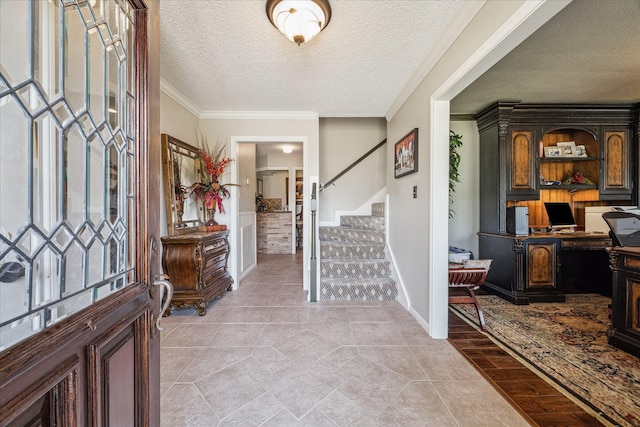 entryway with light tile patterned floors, stairway, a textured ceiling, and crown molding