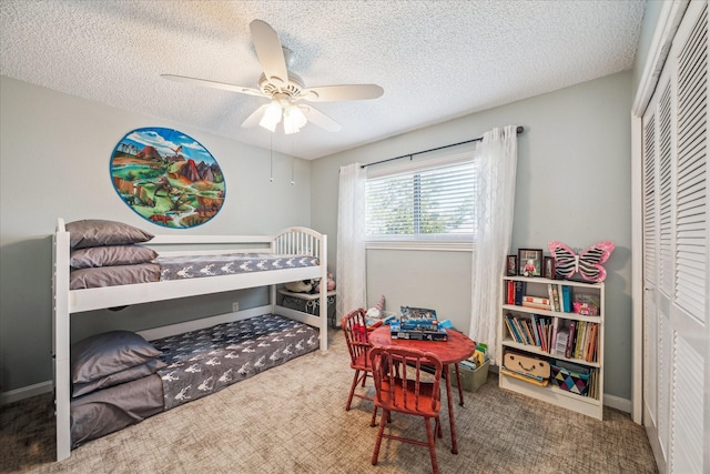 bedroom with a closet, a textured ceiling, carpet flooring, and a ceiling fan