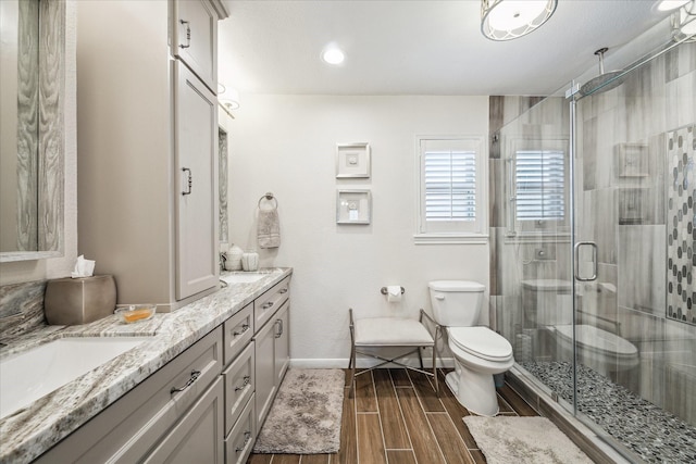 full bathroom with toilet, vanity, a shower stall, baseboards, and wood tiled floor