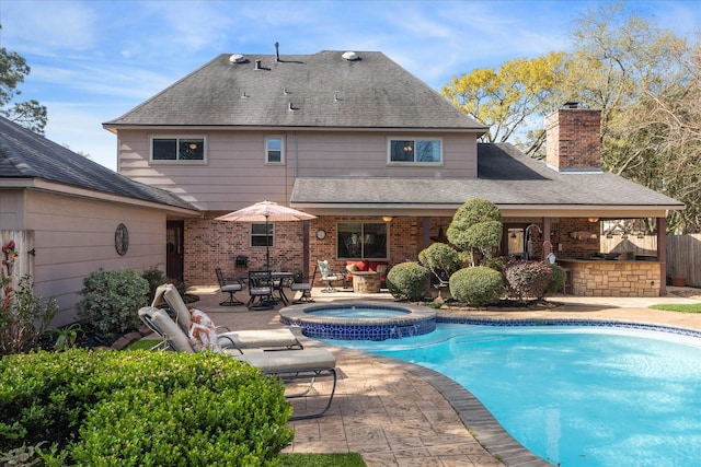 view of swimming pool with a patio, fence, a pool with connected hot tub, and outdoor dry bar