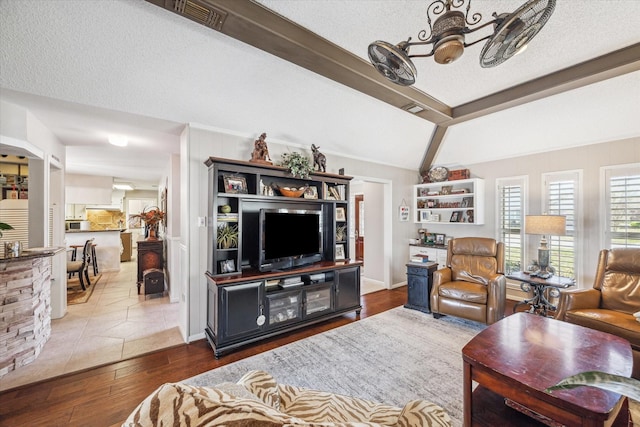 living area featuring visible vents, a notable chandelier, a textured ceiling, wood finished floors, and vaulted ceiling