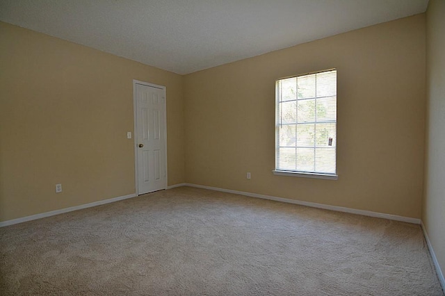 empty room featuring baseboards and light colored carpet