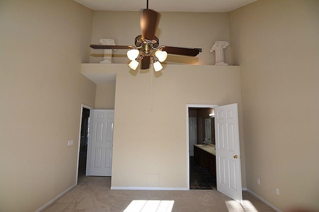 unfurnished bedroom with baseboards, carpet, ensuite bath, and a towering ceiling