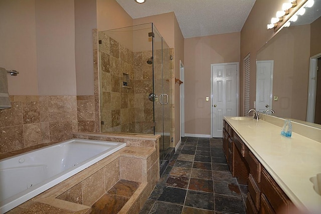 bathroom with double vanity, a stall shower, stone tile flooring, a tub with jets, and a sink