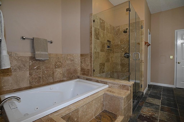 full bathroom featuring stone tile floors, a tub with jets, a stall shower, and baseboards