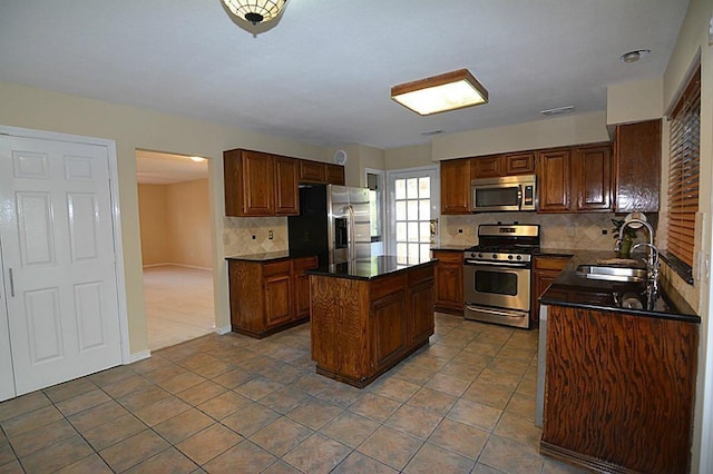 kitchen with visible vents, a sink, appliances with stainless steel finishes, dark countertops, and a center island