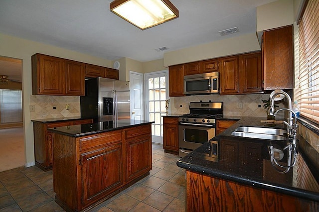 kitchen with a sink, stainless steel appliances, a kitchen island, and visible vents