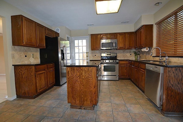 kitchen featuring tile patterned floors, visible vents, a sink, a center island, and stainless steel appliances