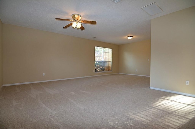 empty room with baseboards, light colored carpet, a ceiling fan, and a textured ceiling