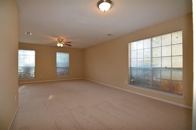 unfurnished room featuring visible vents, baseboards, ceiling fan, light carpet, and a textured ceiling