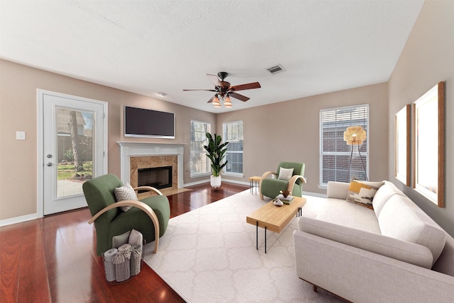 living room featuring a wealth of natural light, visible vents, dark wood finished floors, and ceiling fan