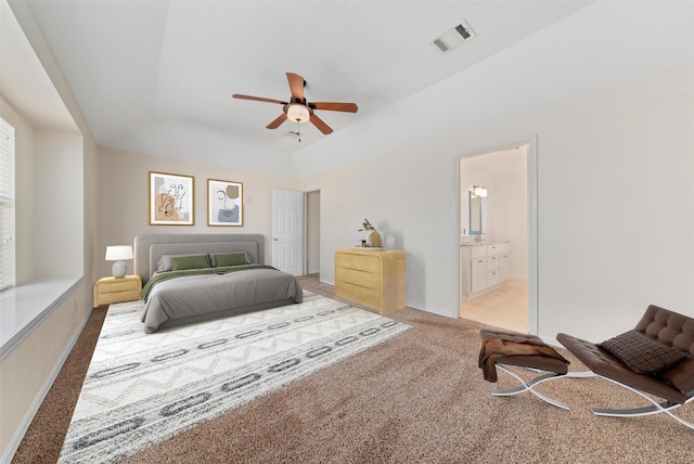 bedroom featuring visible vents, connected bathroom, carpet, a raised ceiling, and a ceiling fan