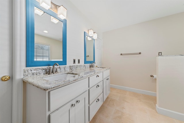 bathroom with tile patterned flooring, double vanity, baseboards, and a sink