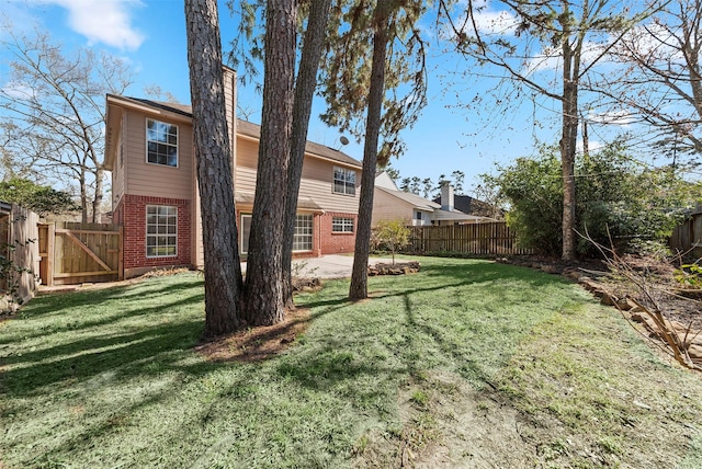 exterior space featuring brick siding, a fenced backyard, and a lawn