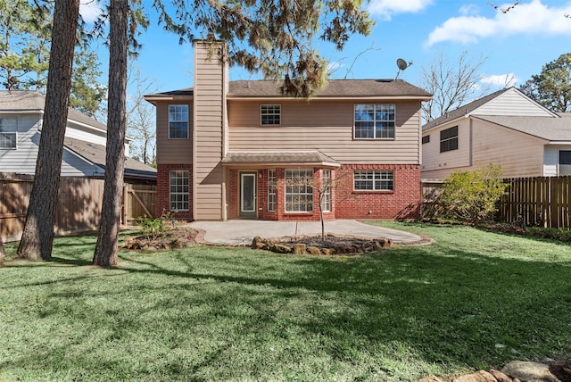 back of property with a patio, a yard, a fenced backyard, a chimney, and brick siding