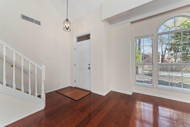 entryway with a notable chandelier, visible vents, baseboards, and wood finished floors