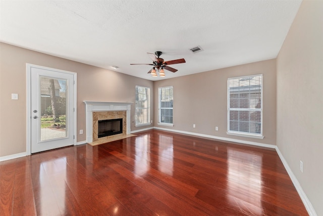 unfurnished living room featuring wood finished floors, a healthy amount of sunlight, and ceiling fan