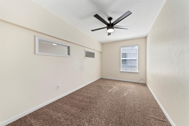 spare room with baseboards, ceiling fan, carpet flooring, a textured wall, and a textured ceiling