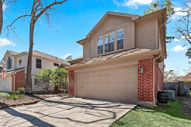 traditional-style home with driveway, roof with shingles, an attached garage, central air condition unit, and brick siding